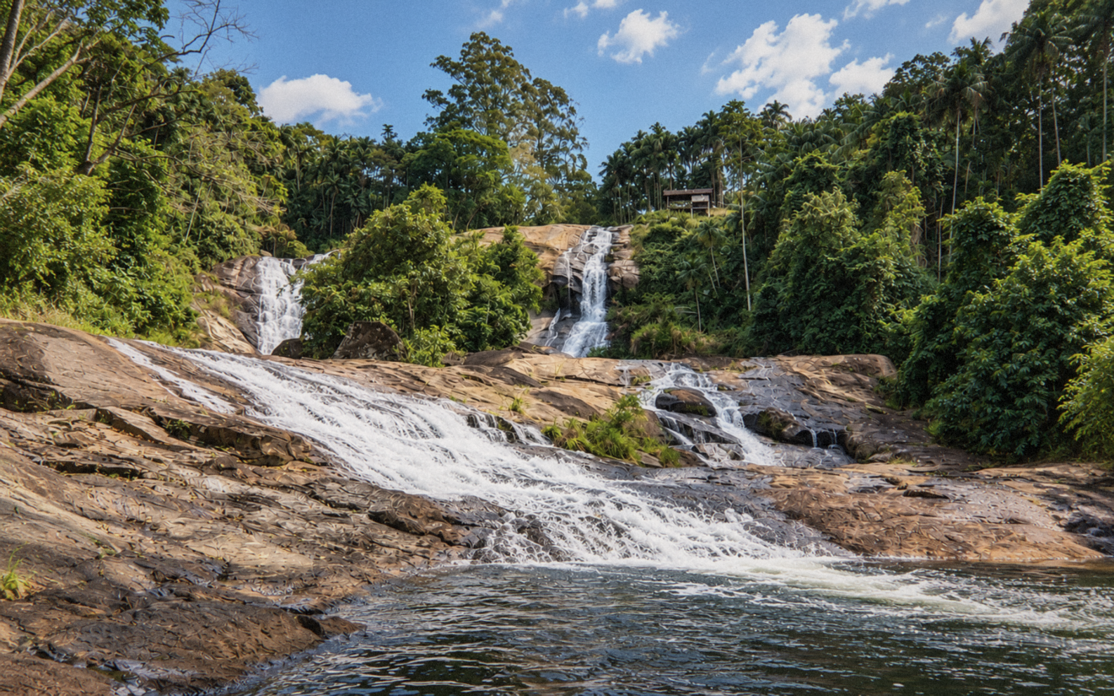 Paisagem de uma cachoeira com várias quedas entre rochas e árvores